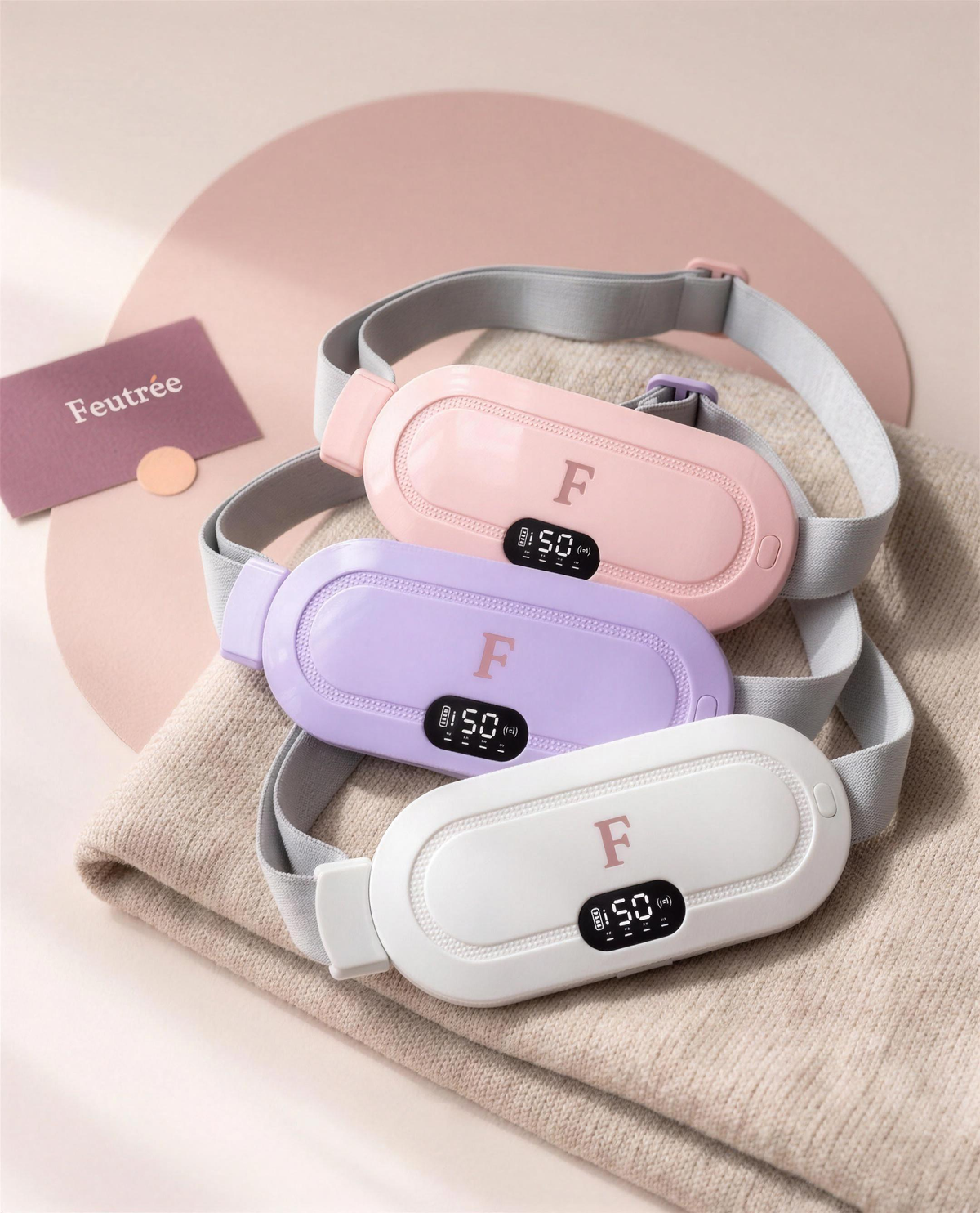 Trio de ceintures chauffantes Feutrée, rose, lilas et blanche, avec une carte portant le logotype Feutrée
